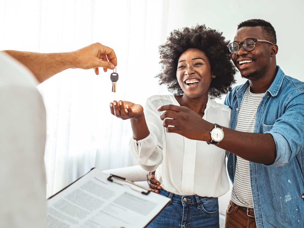 Salesperson handing keys to new homeowners in house