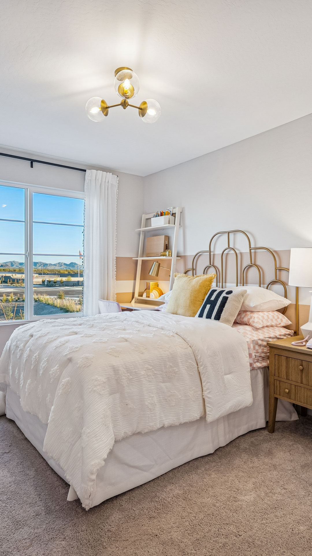 Stunning pink and white themed bedroom with gold iron day bed & study desk with view of the white tank mountains outside the window at Manzanita at Teravalis Ponderosa model home in Buckeye AZ New Homes for sale and new construction in buckeye AZ. 