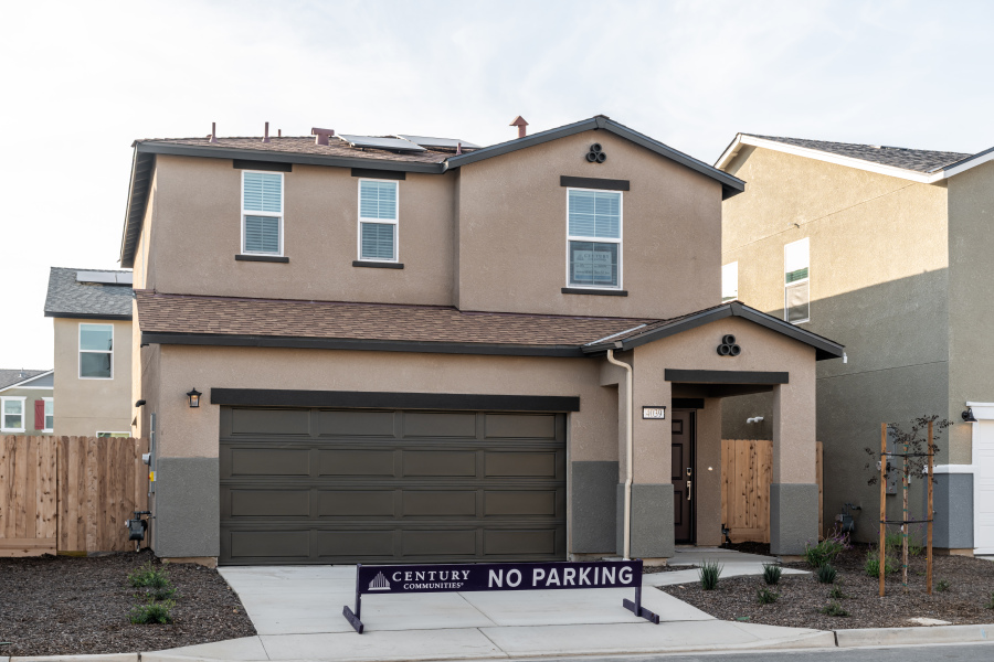 A house with garages and a sign in front of it.