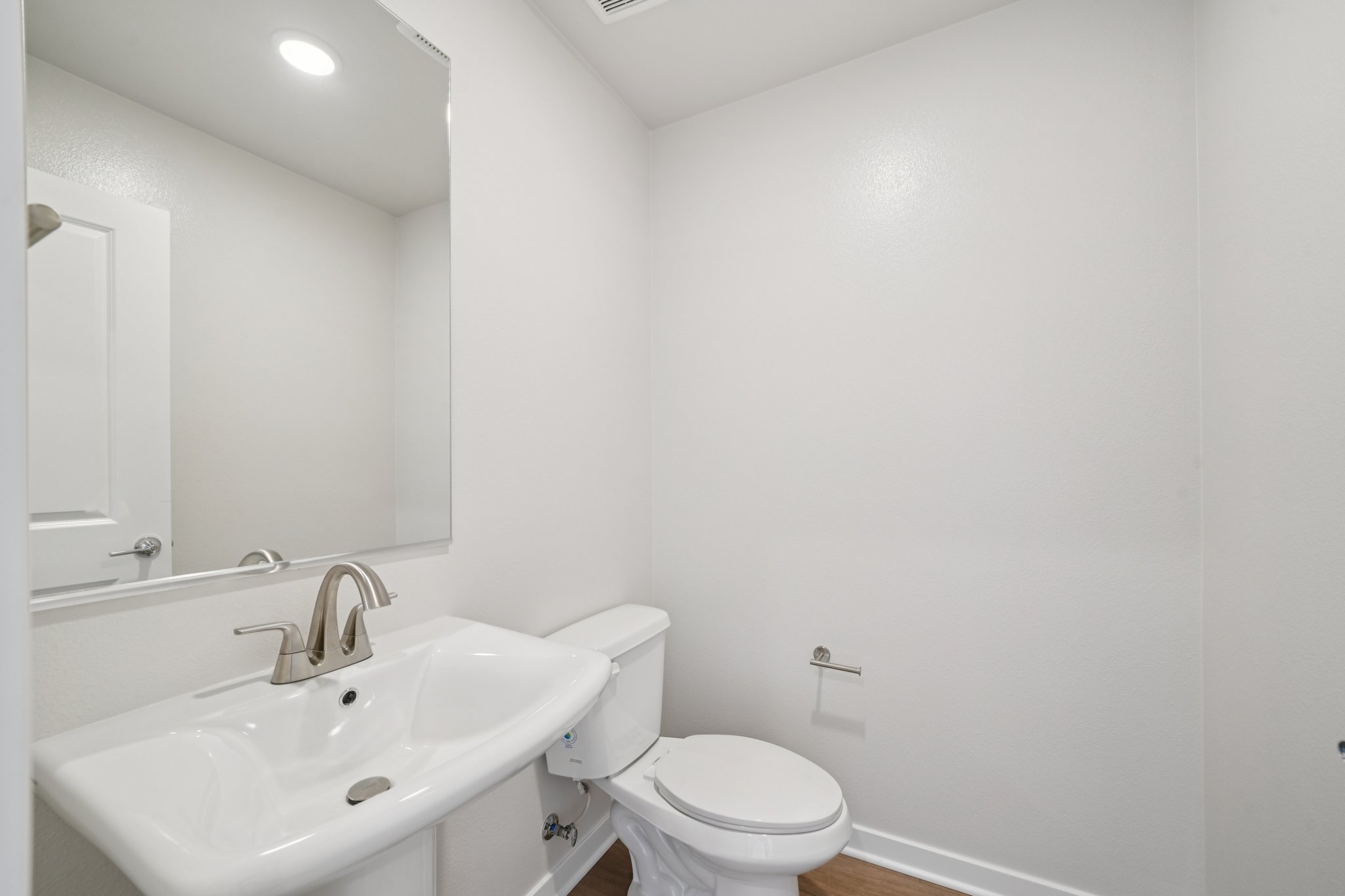A bathroom with a sink toilet and mirror.