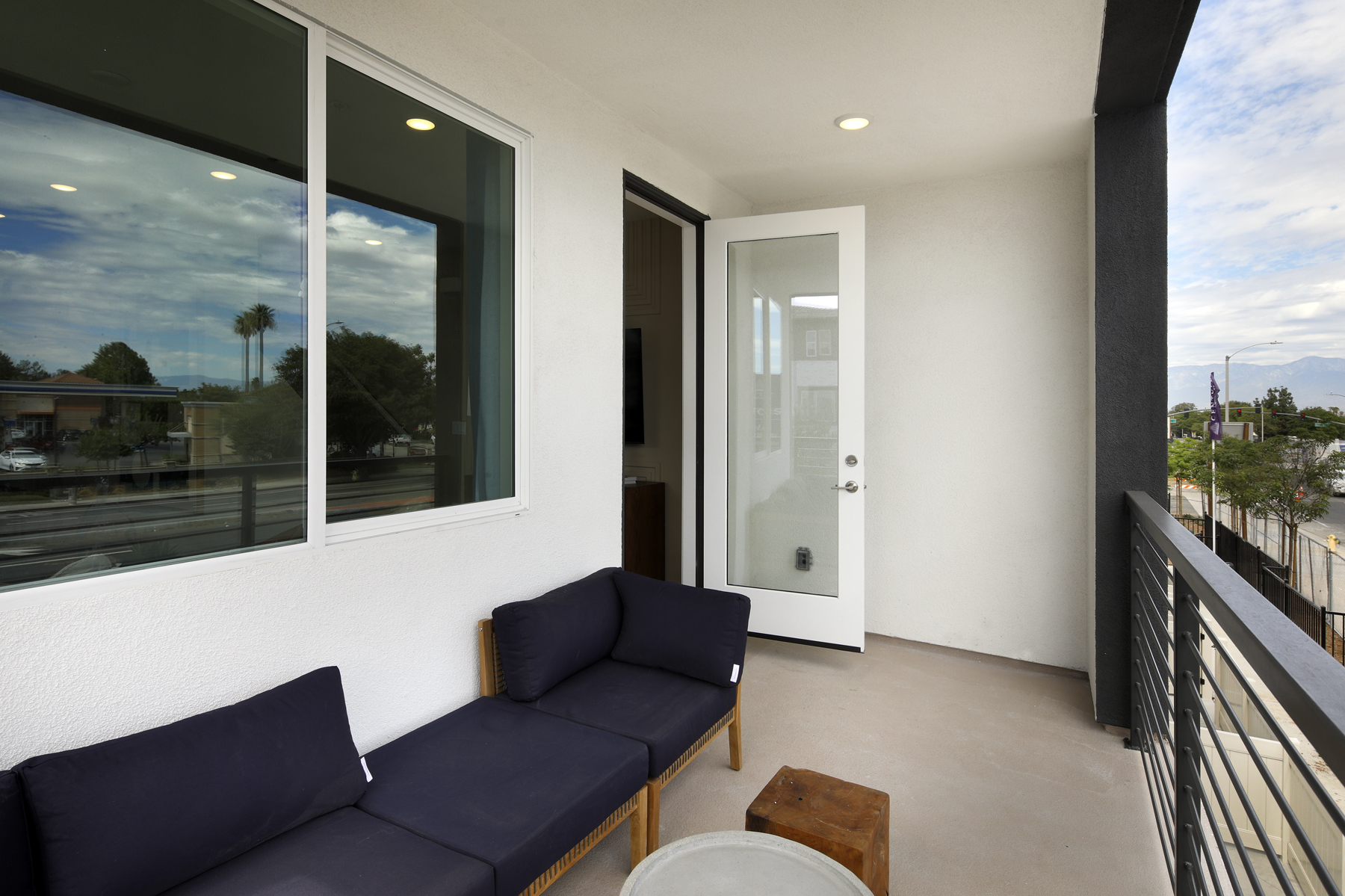 A room with a balcony and a patio with a couch and a table.