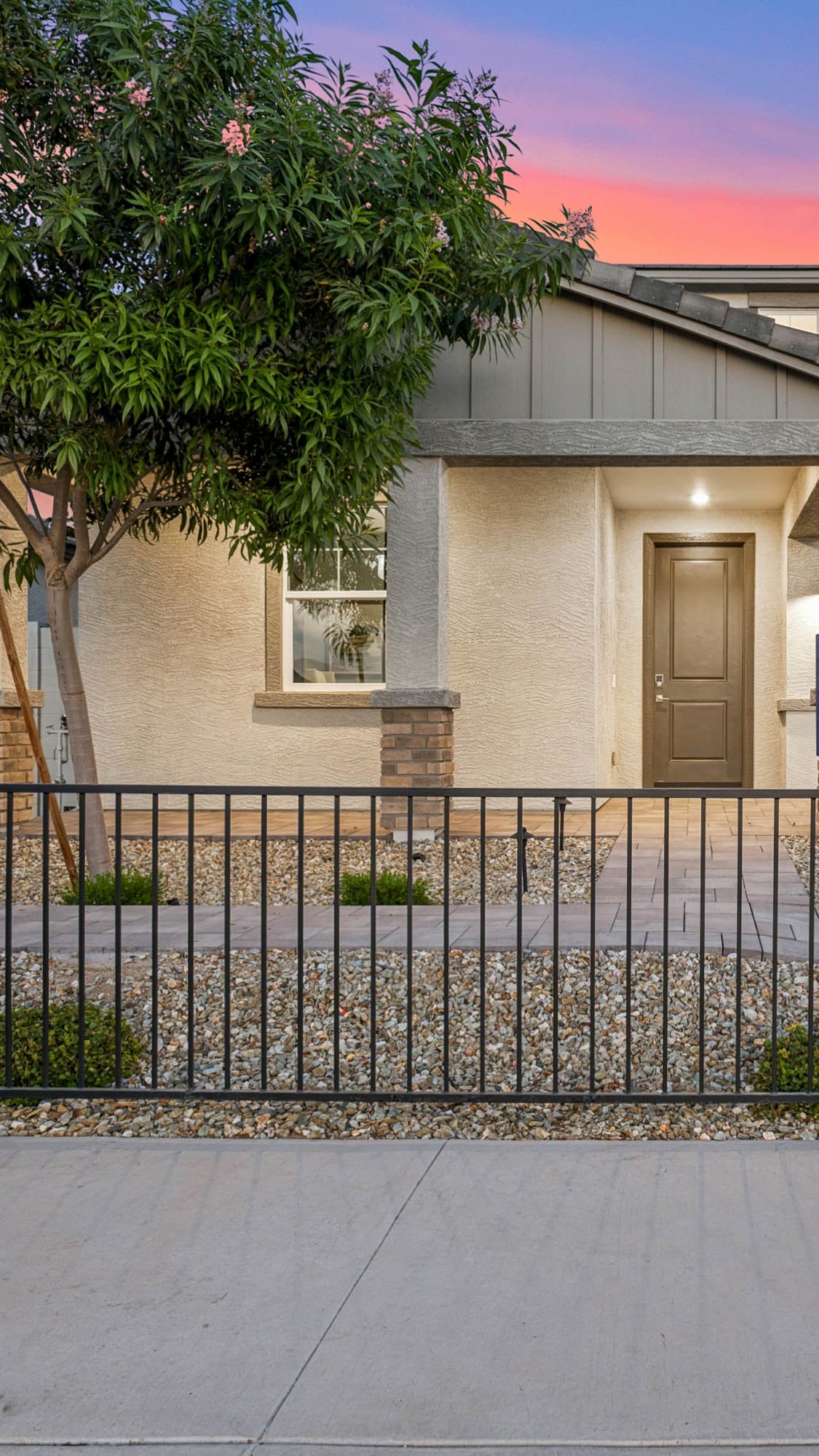 Front of Marion Model Home in Surprise AZ North Copper Canyon Community during twilight with large tree in front. new construction dream homes for sale at north copper canyon in Surprise az