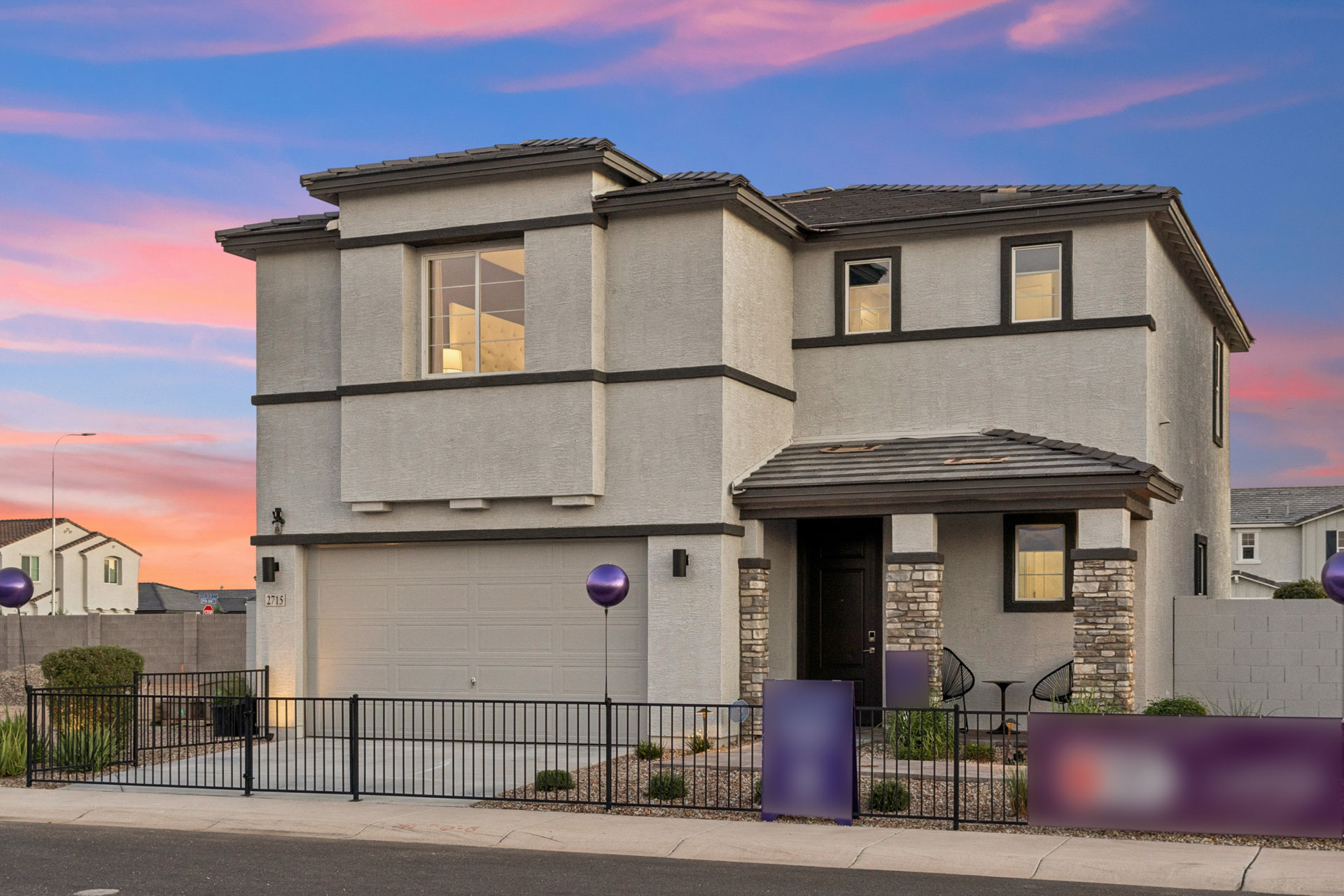 A grey house with a black fence.