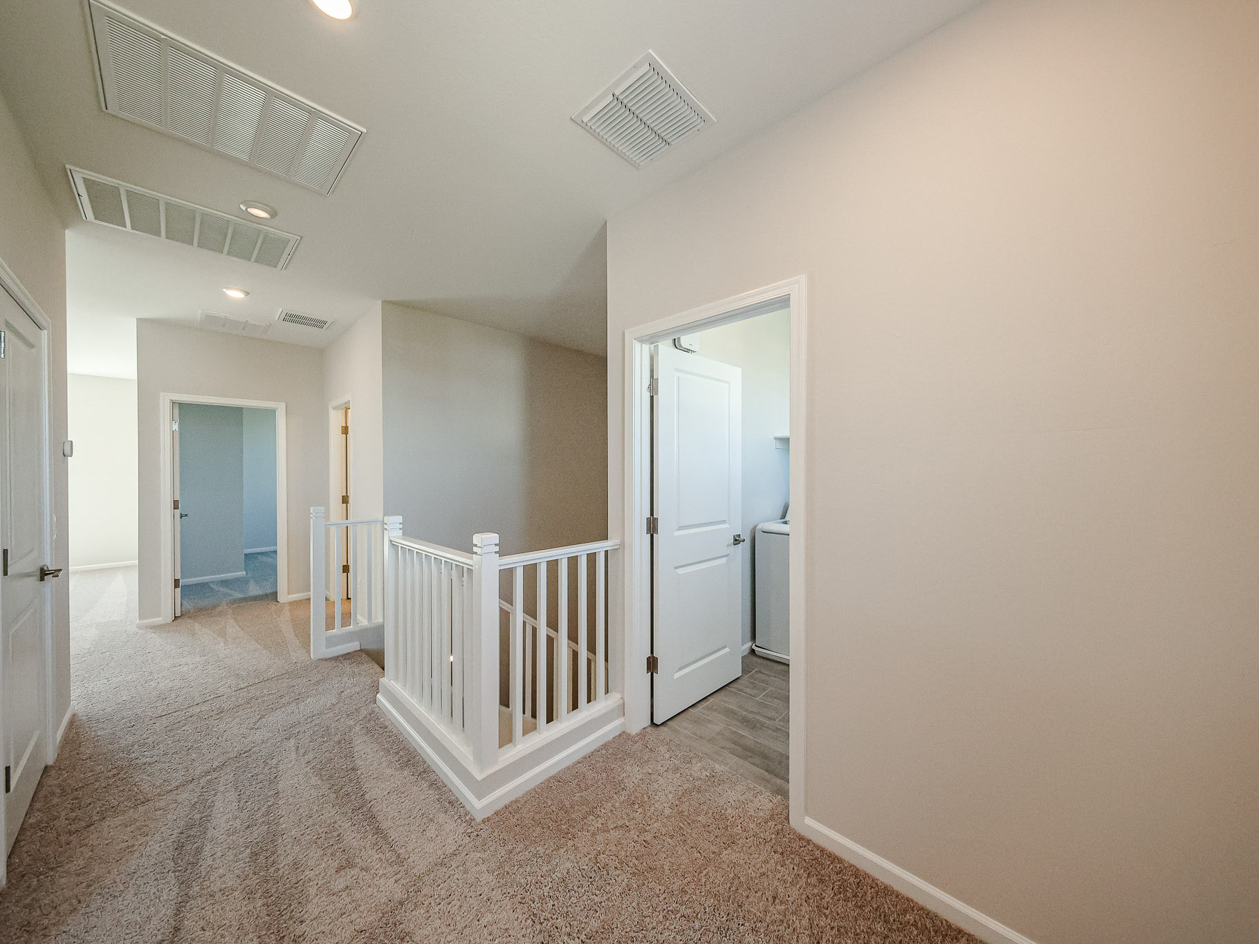 A room with a white railing and a white door.