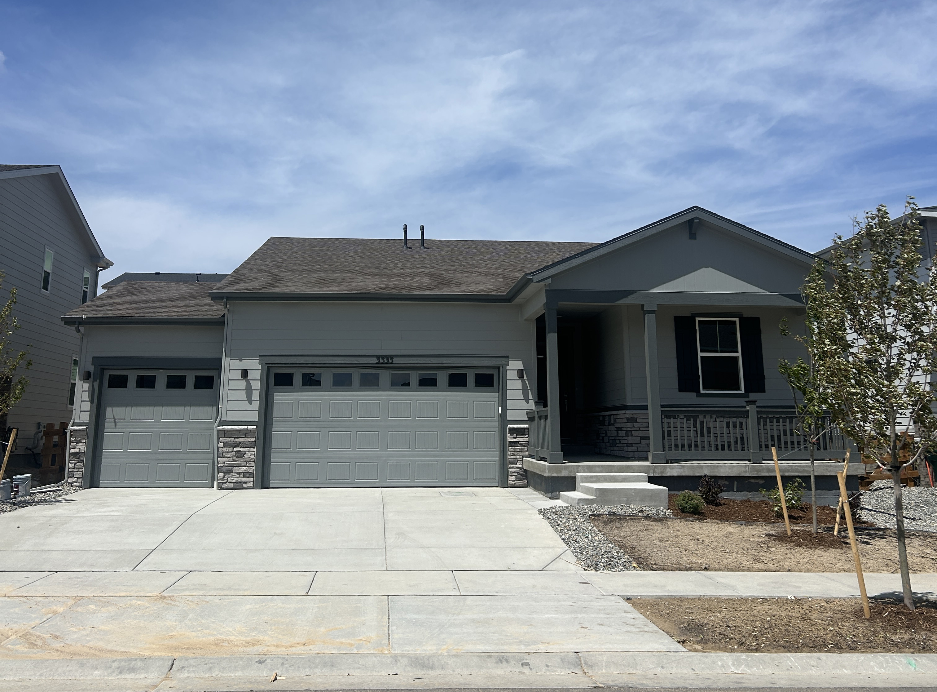 A house with garages and a tree in the front.