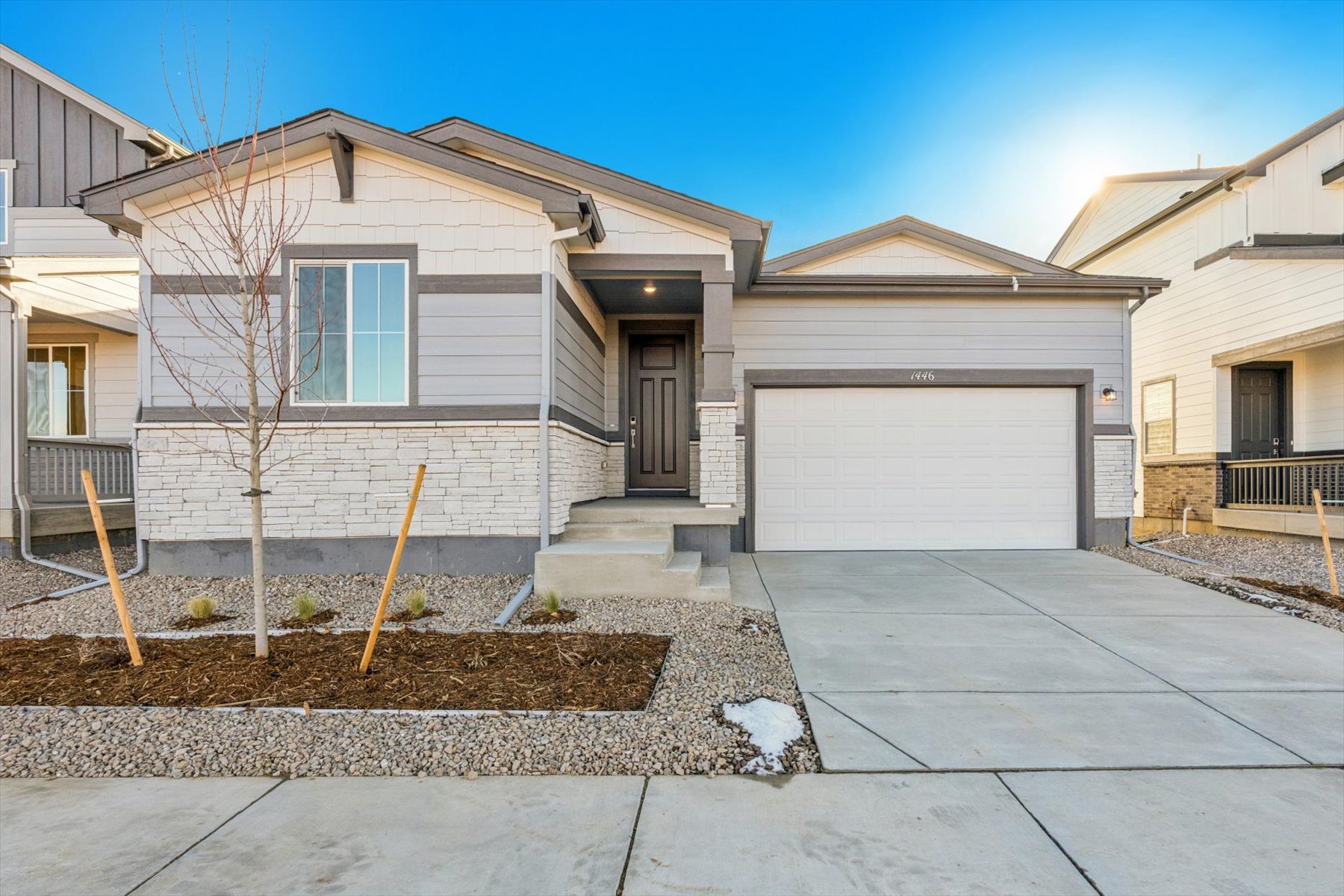A house with garages and a tree in the front.