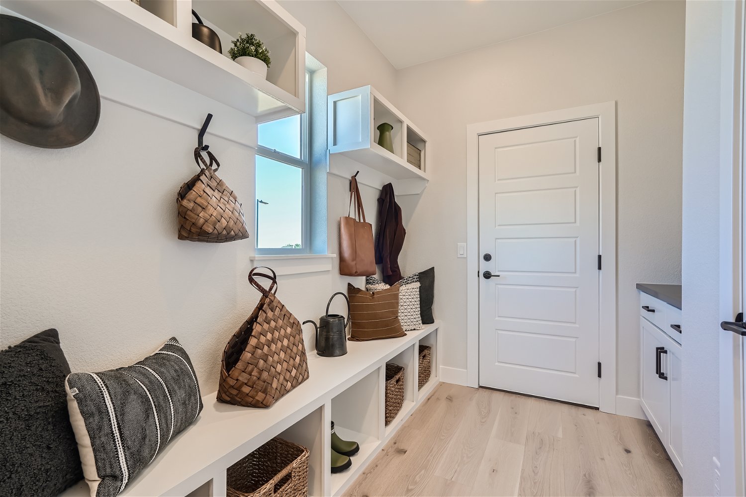 A room with a white door and shelves with baskets and a white door.
