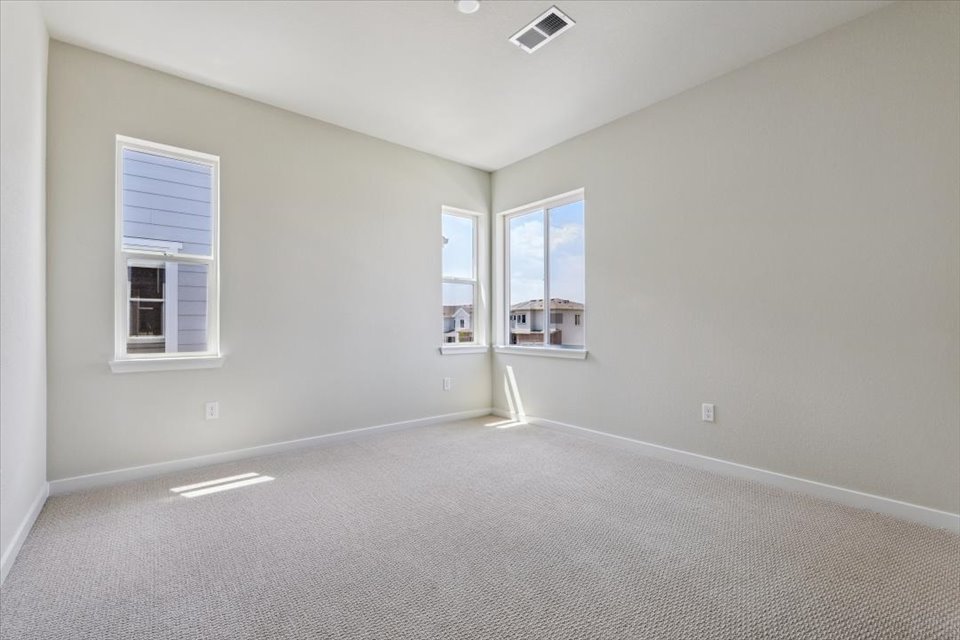A room with a white carpet and windows.