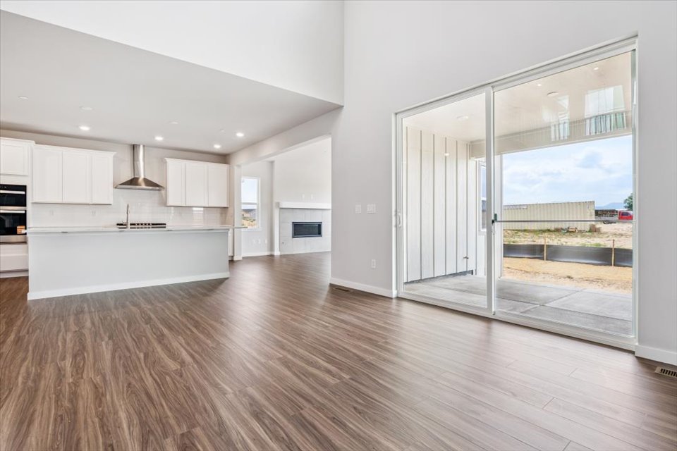 A large white room with a large glass door and a wood floor.