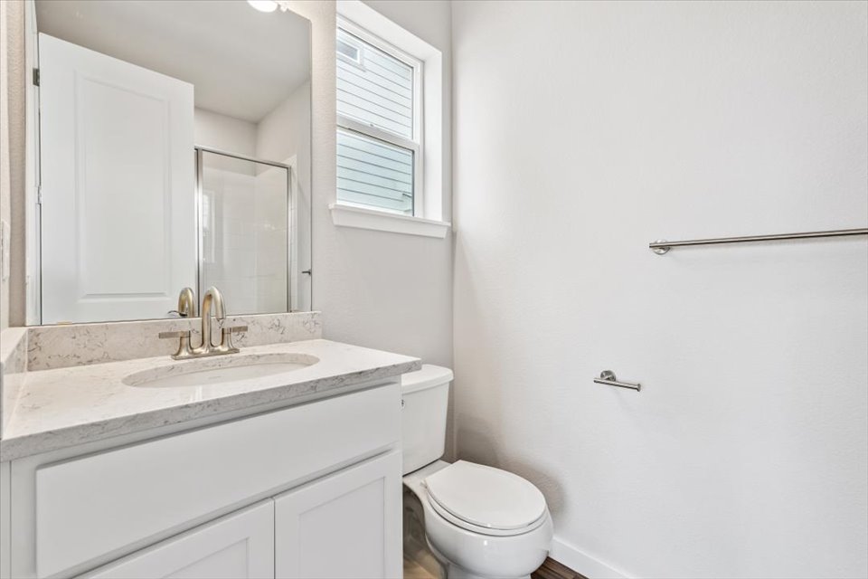 A bathroom with a sink toilet and mirror.