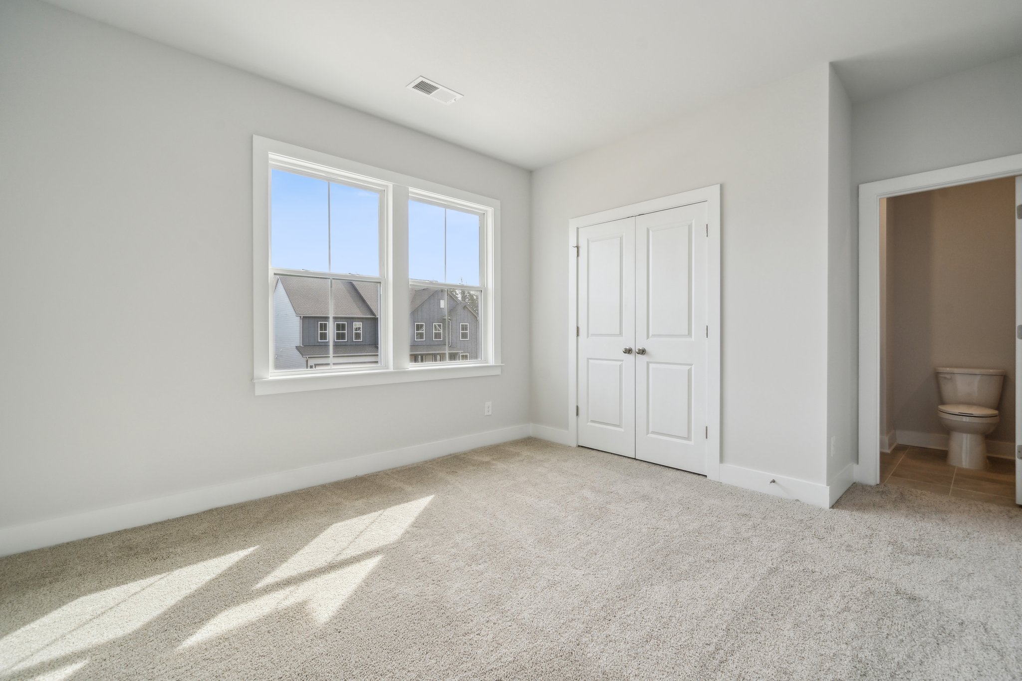 A large white room with a toilet and a window.