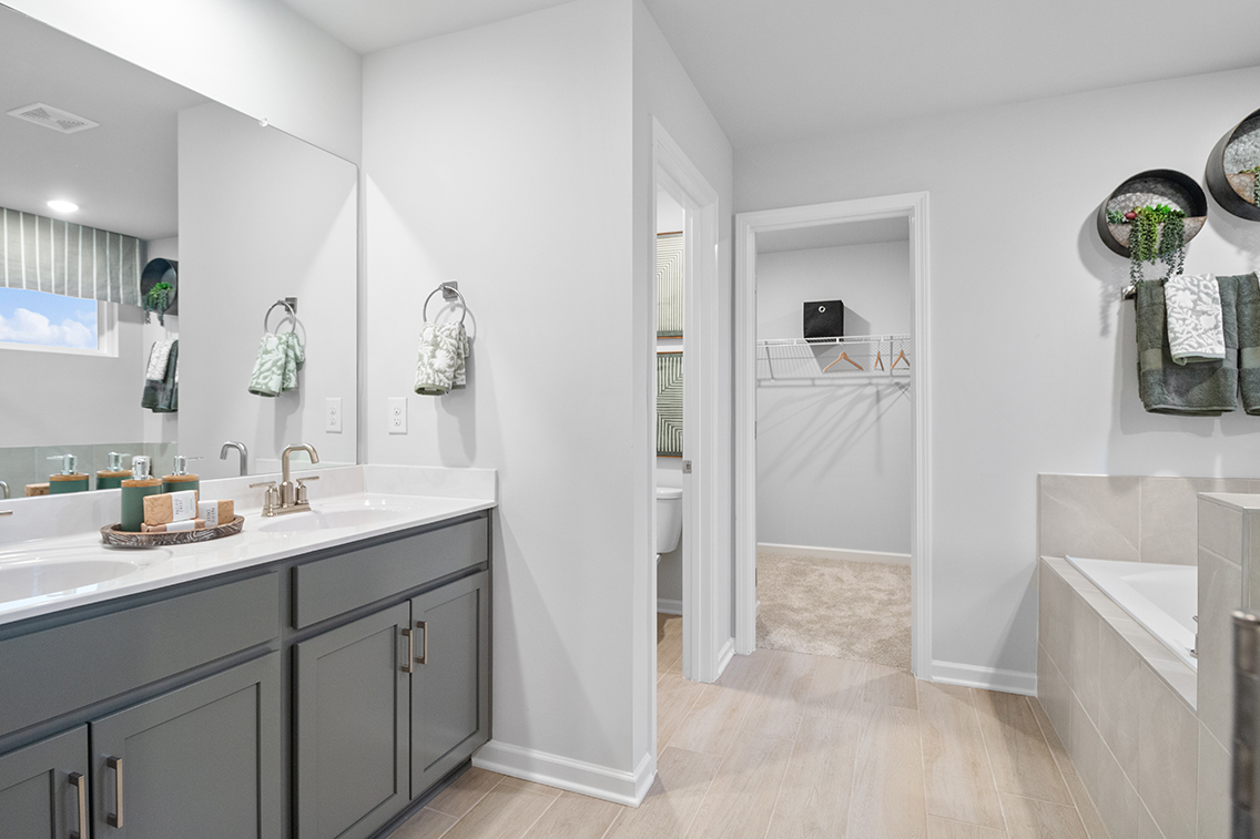 A bathroom with a tub sink and mirror.