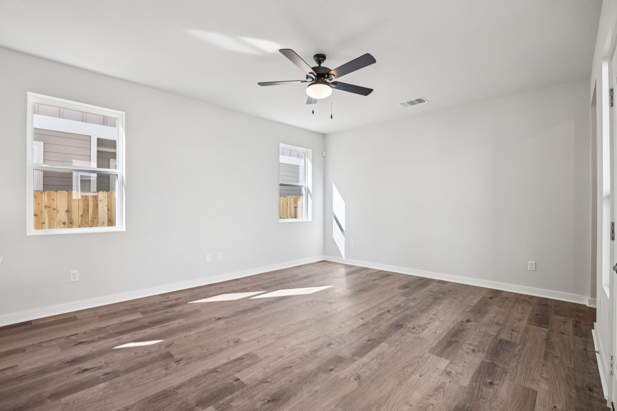 A room with a wood floor and a ceiling fan.