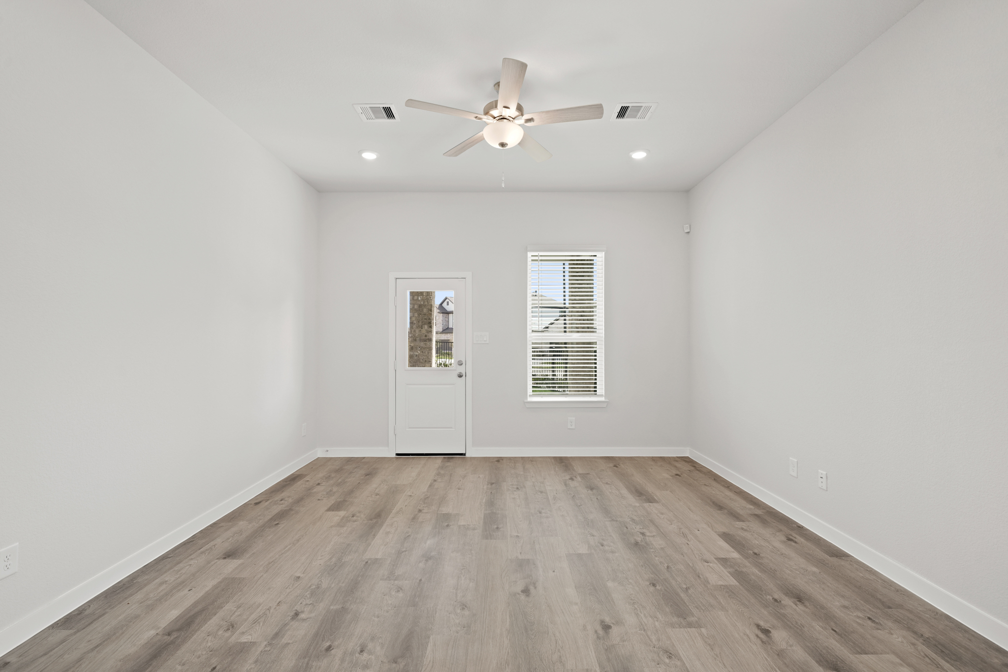 A room with a ceiling fan and a wood floor.