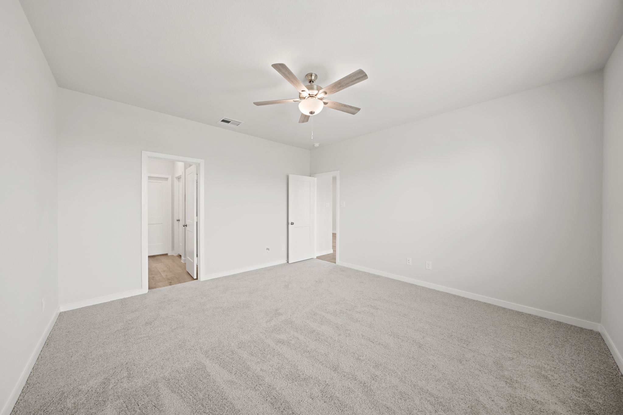A room with a ceiling fan and a carpet.