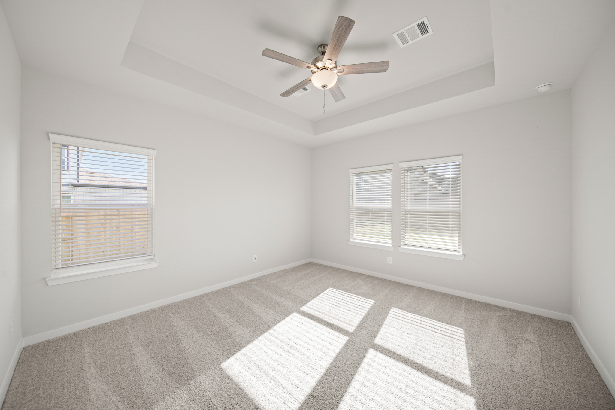 A room with a ceiling fan and a rug.
