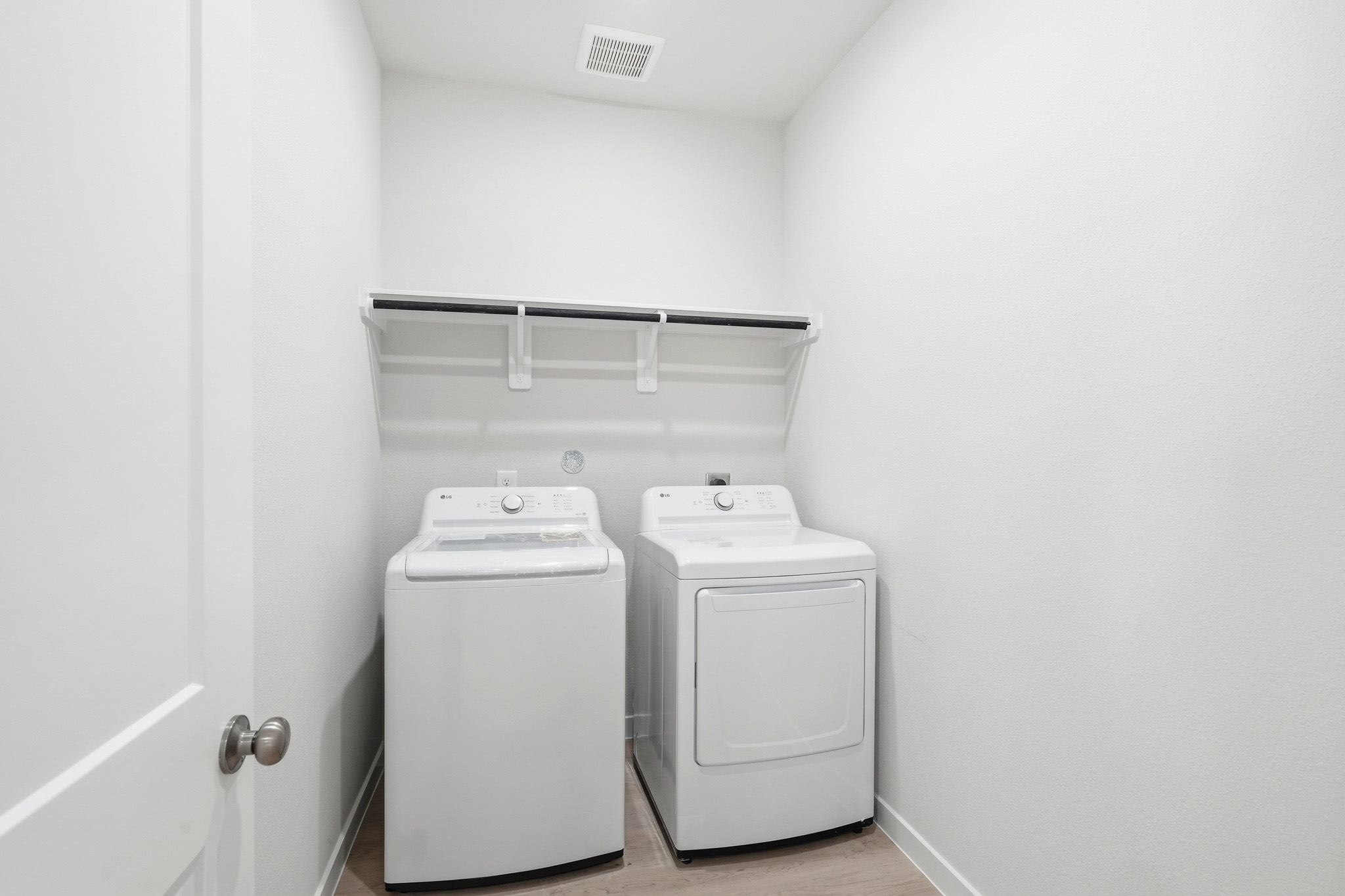 A white room with a washing machine and a white door.