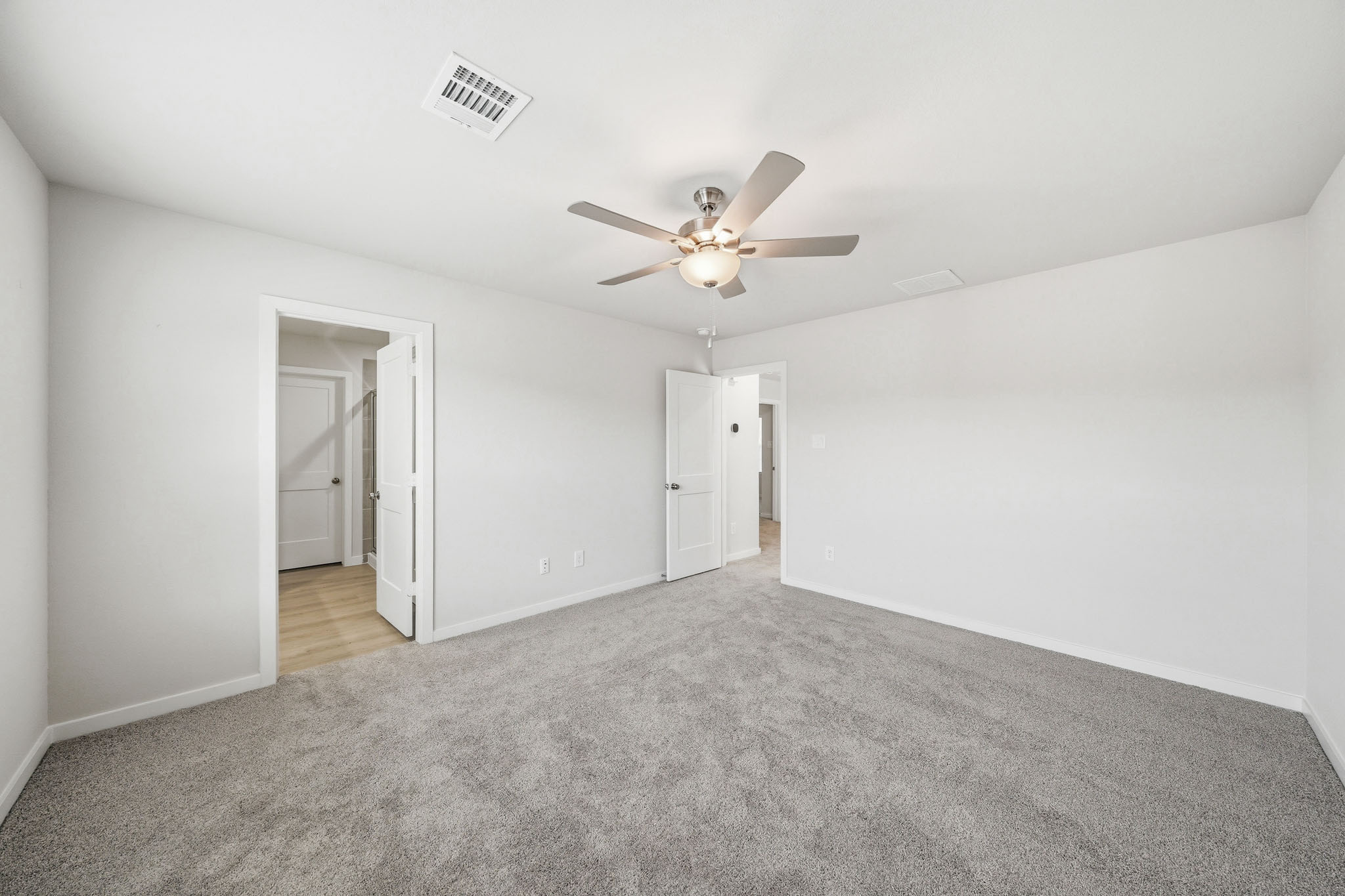 A room with a ceiling fan and a carpet.
