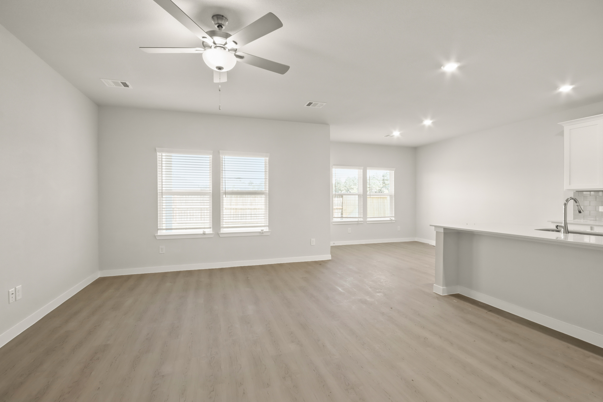 A large empty room with a ceiling fan and a wood floor.