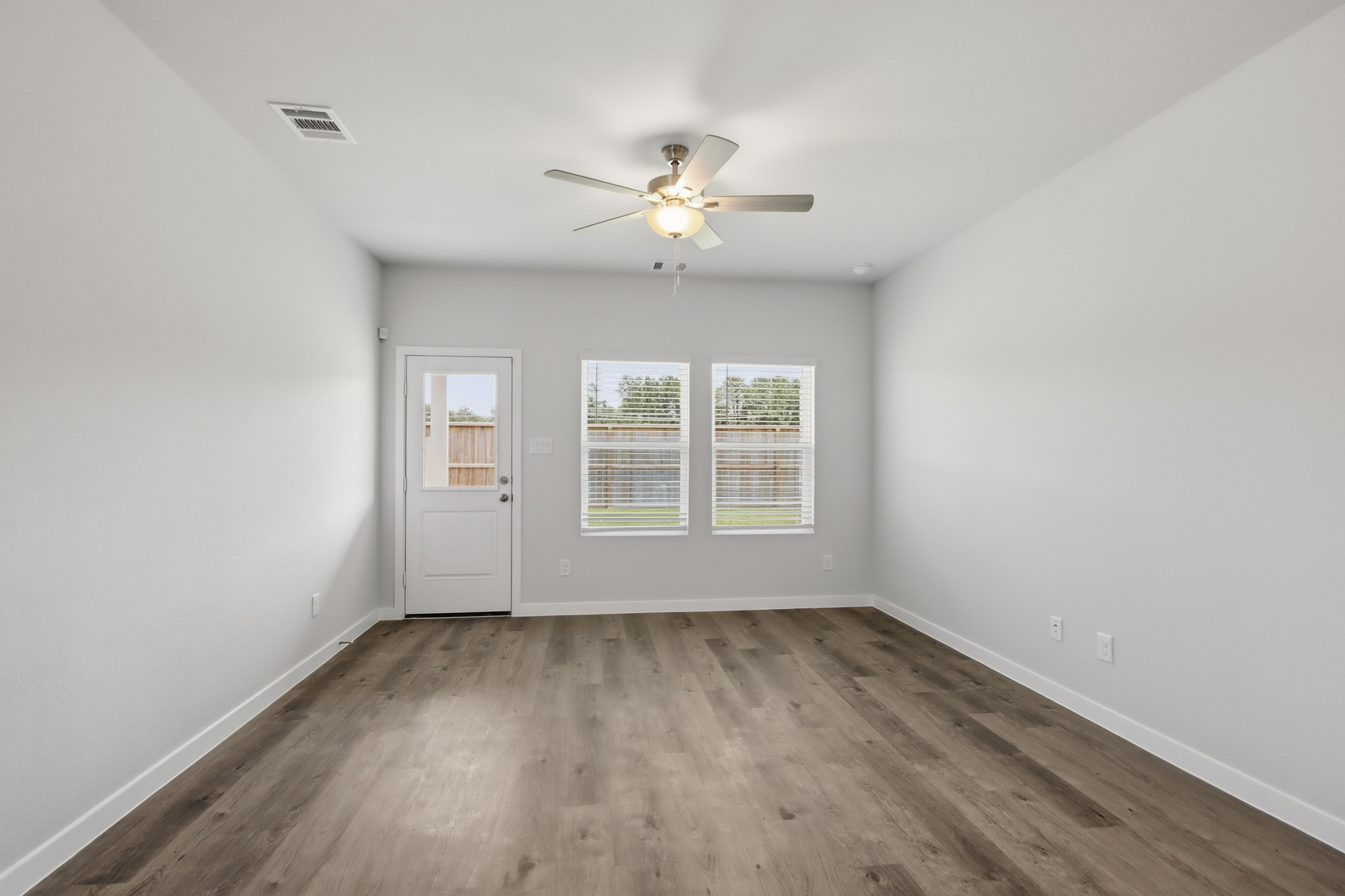 A room with a ceiling fan and a wood floor.