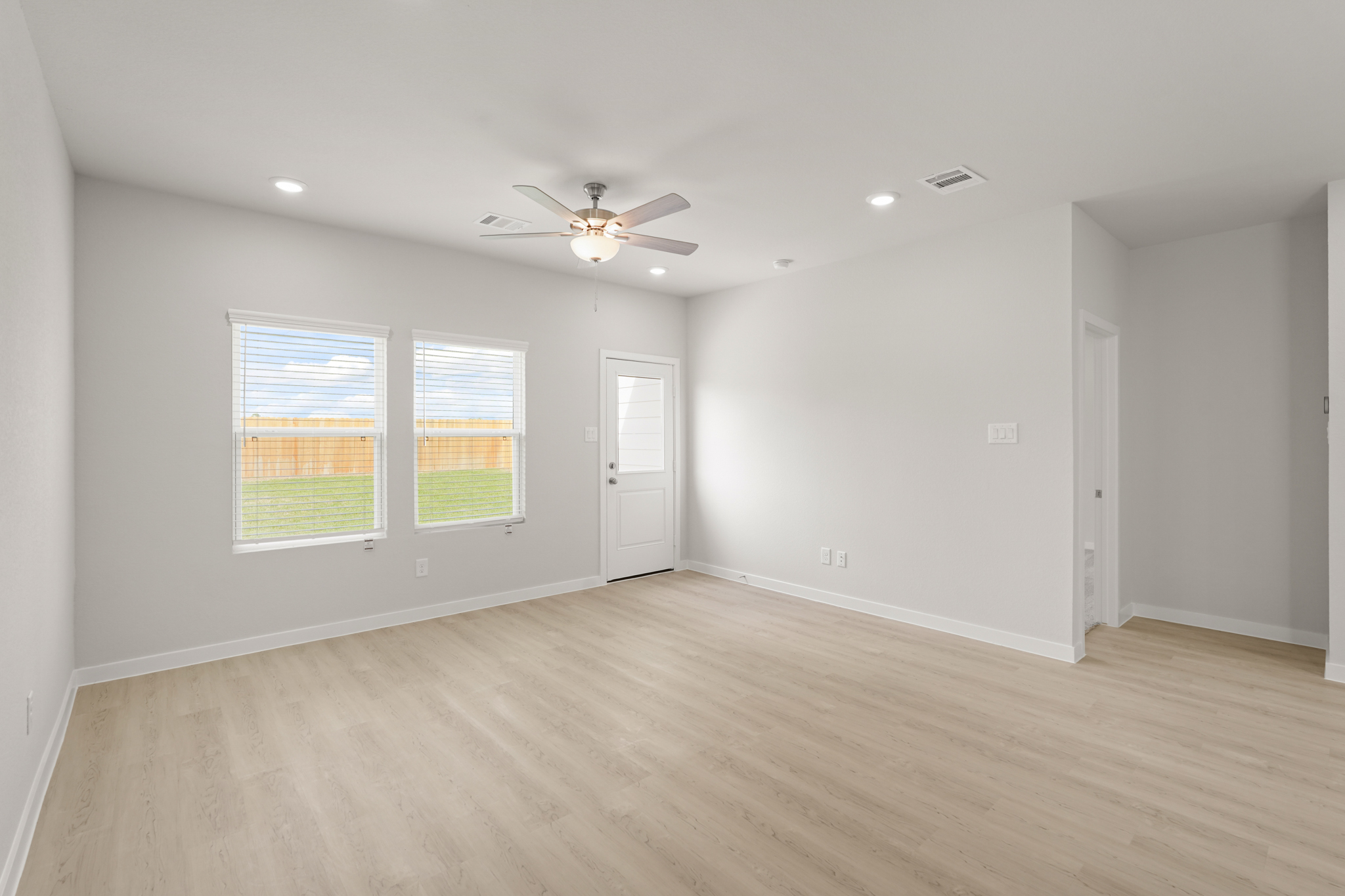 A room with a ceiling fan and a wood floor.