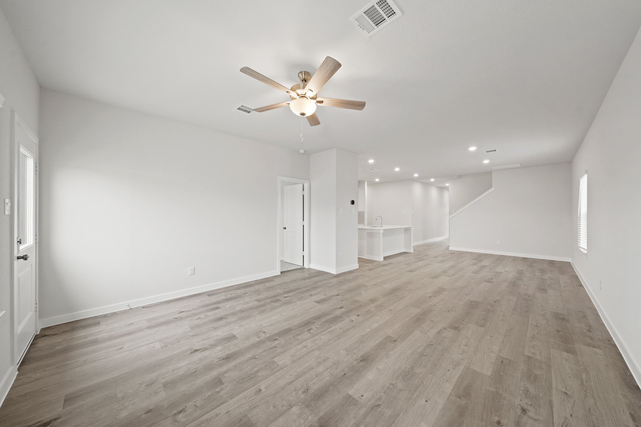 A room with a ceiling fan and wood floors.