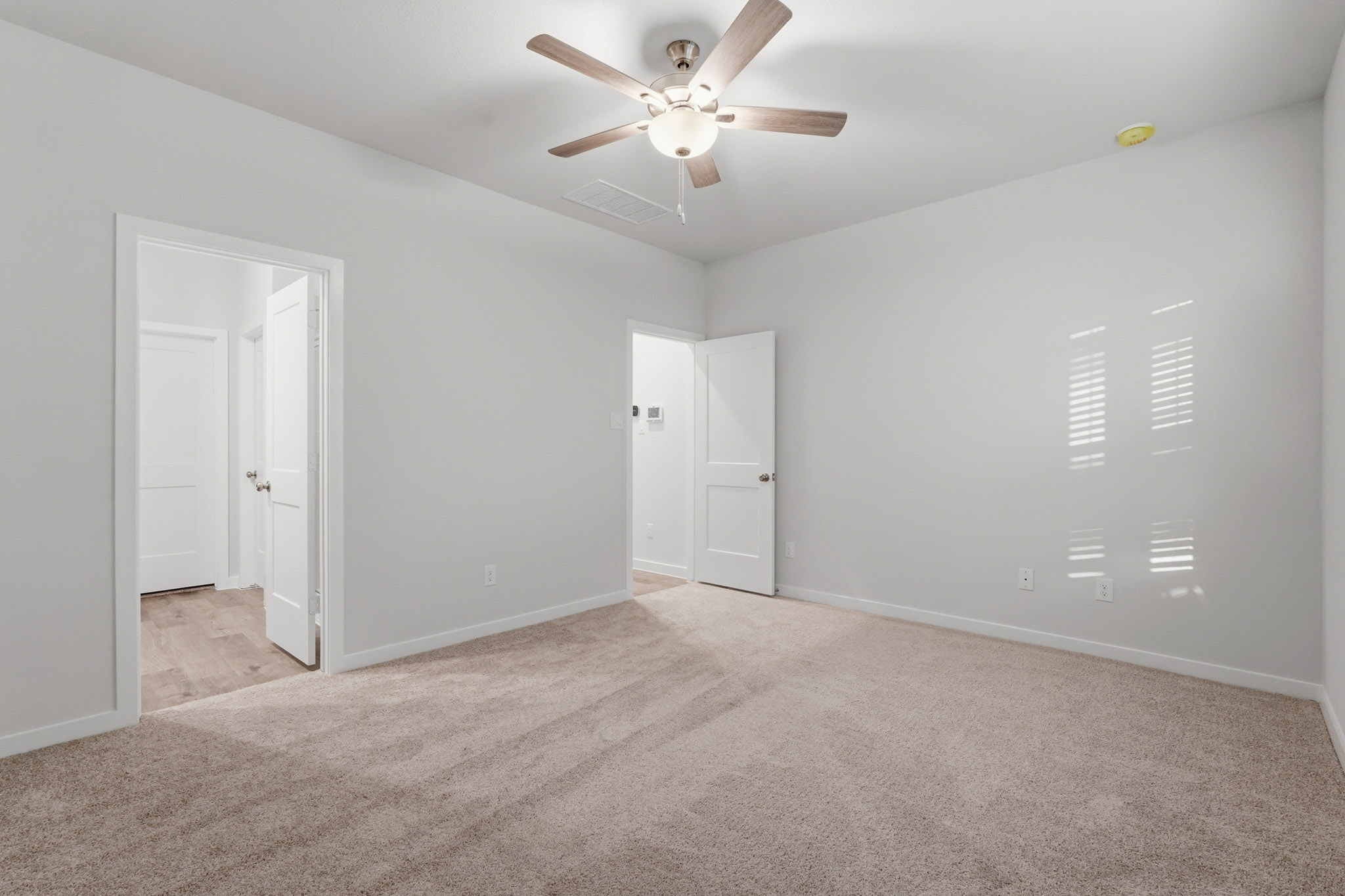 A room with a ceiling fan and white doors.