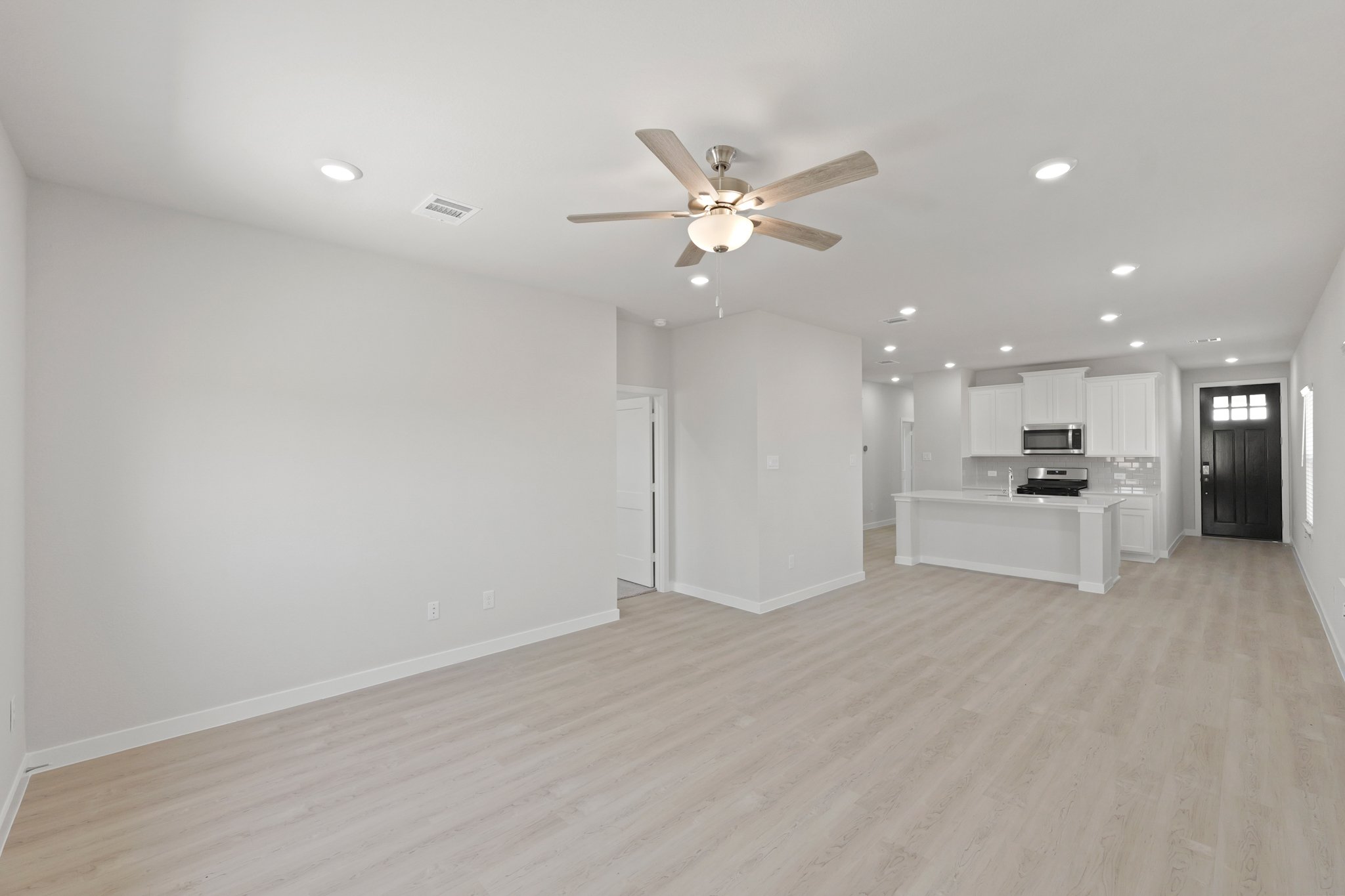 A large empty room with a ceiling fan and a wood floor.