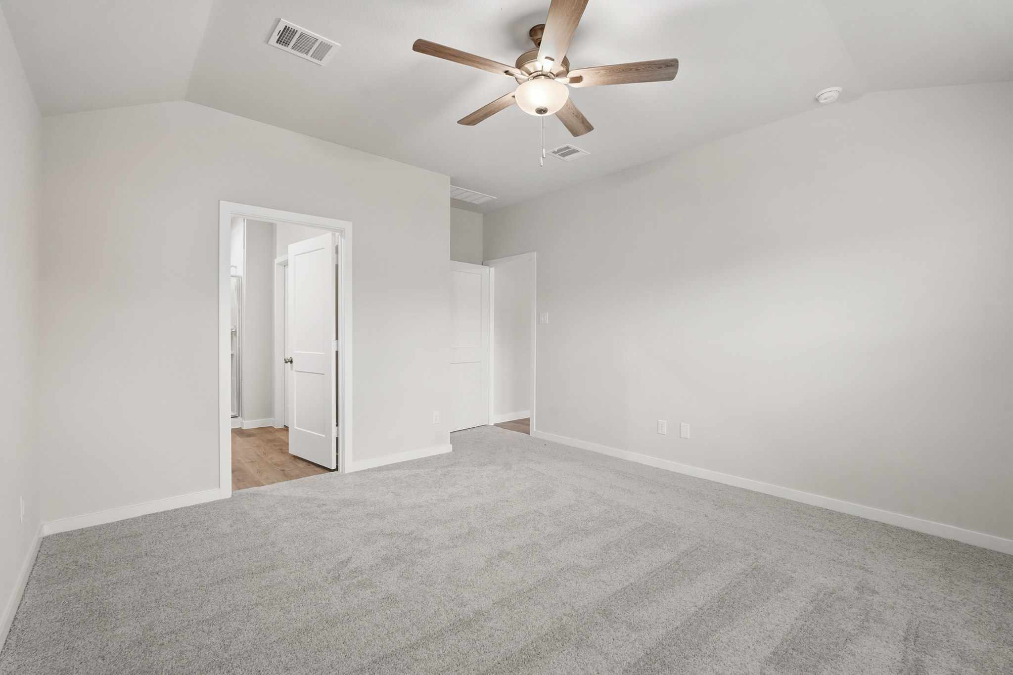 A room with a ceiling fan and a carpet.