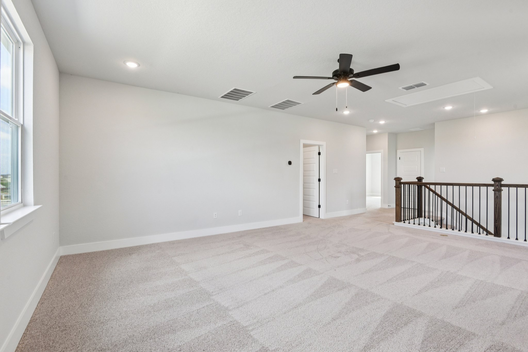 A room with a ceiling fan and a railing.