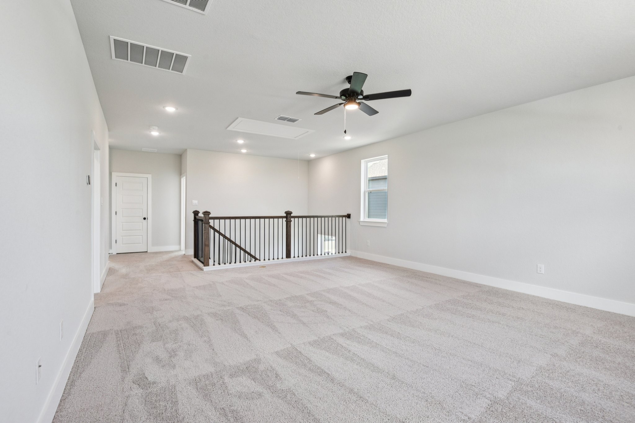 A room with a carpet and a ceiling fan.