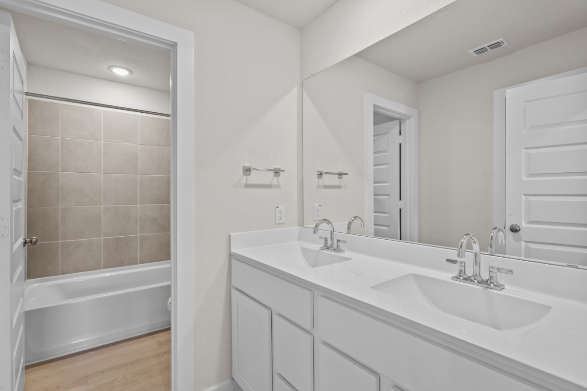 A bathroom with a tub sink and a mirror.