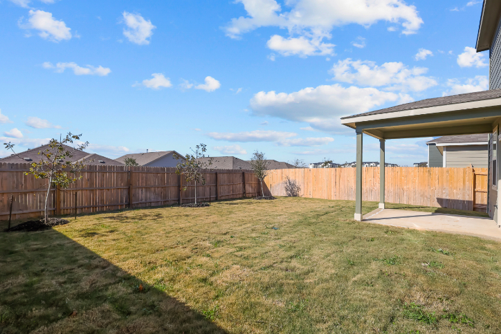 A fenced in yard with a house and trees in the background.