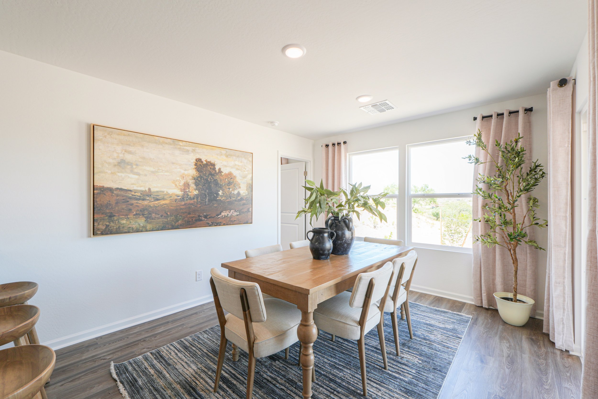 A dining room table with chairs and a painting on the wall.