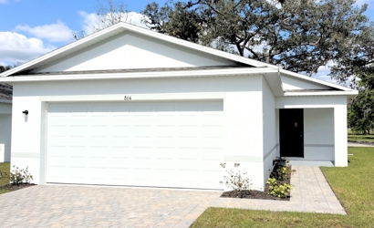 A white garage with a brick walkway.